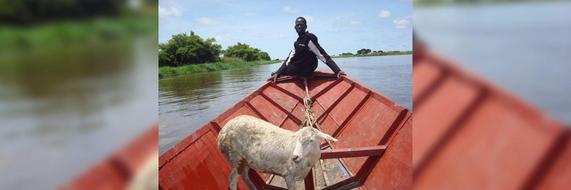 African man on the edge of the boat with live goat